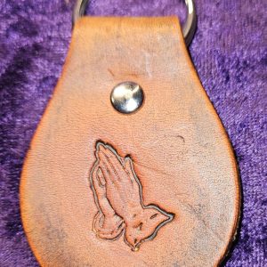 Leather dyed antique brown with praying hands stamp approximately 3 inches long by 2 inches wide.