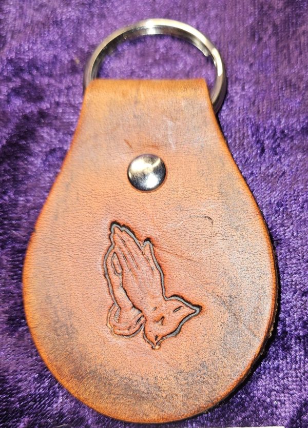 Leather dyed antique brown with praying hands stamp approximately 3 inches long by 2 inches wide.