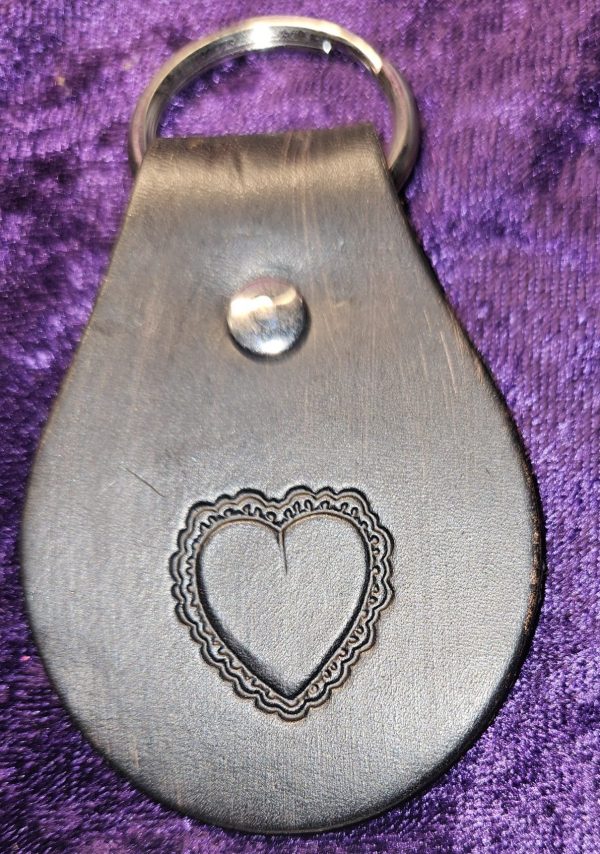 Leather dyed black with heart stamp approximately 3 inches long by 2 inches wide.