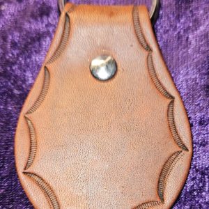 Leather dyed antique brown with stamped edging approximately 3 inches long by 2 inches wide.