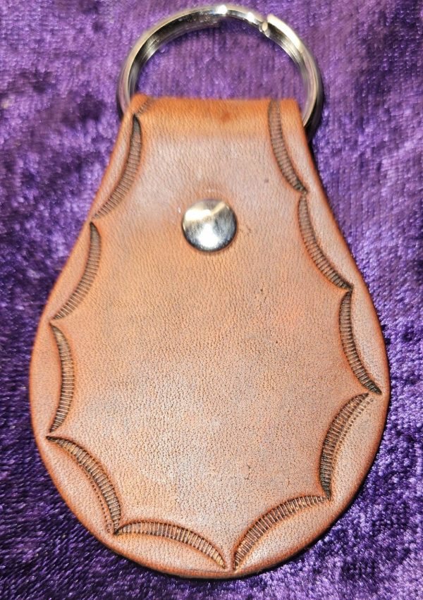 Leather dyed antique brown with stamped edging approximately 3 inches long by 2 inches wide.