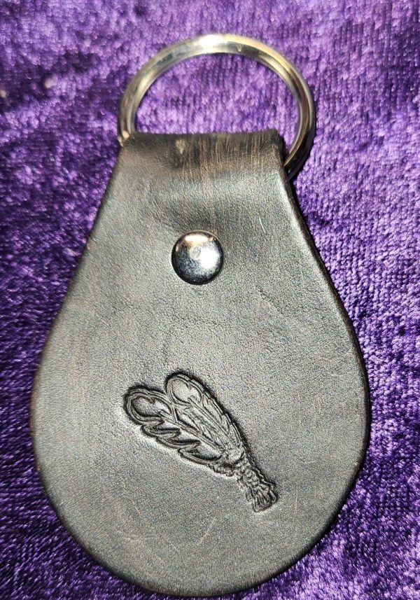 Leather dyed black with feather stamp approximately 3 inches long by 2 inches wide.