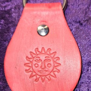 Leather dyed red with sun faced stamp approximately 3 inches long by 2 inches wide.