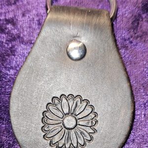 Dyed black leather with flower stamp approximately 3 inches long by 2 inches wide.