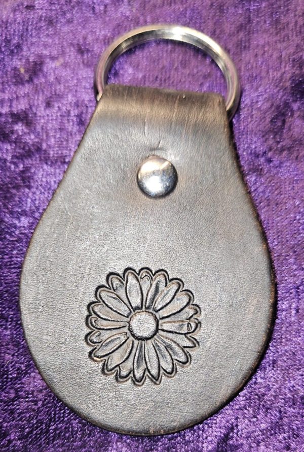 Dyed black leather with flower stamp approximately 3 inches long by 2 inches wide.